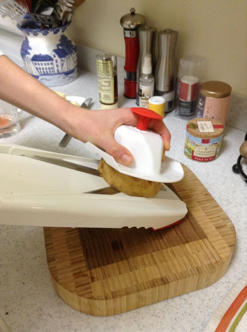 Using the v-slicer, slice the potatoes about a 1/8 inch thick