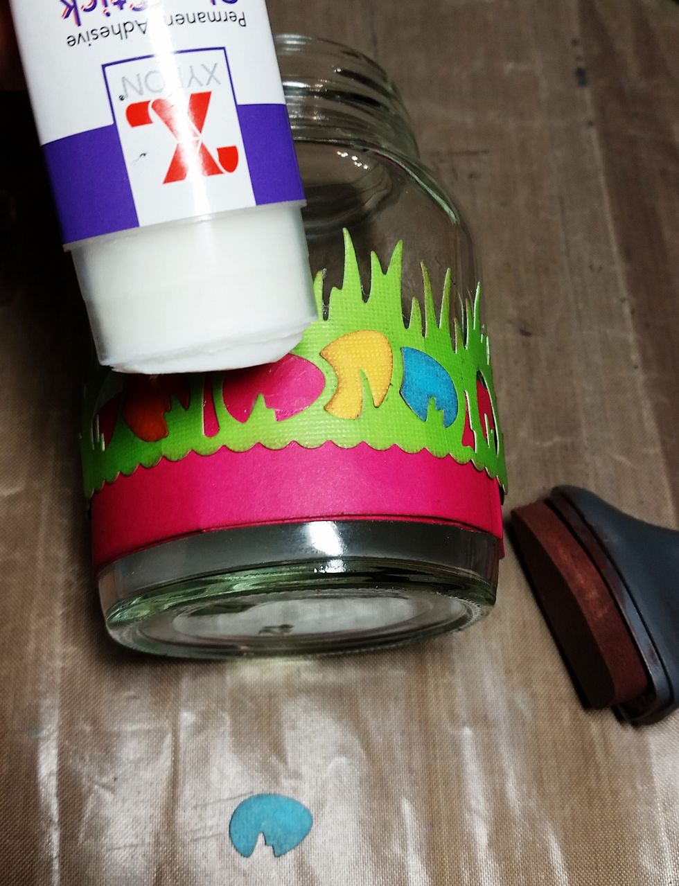 Using the Xyron glue stick I applied a light coat of glue in the egg holes of the die cut and inserted the turquoise, orange, and yellow eggs (inked in brown) in the spaces.