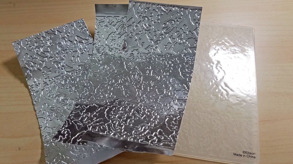Using three different colors of alcohol ink, color each embossed metal sheet.