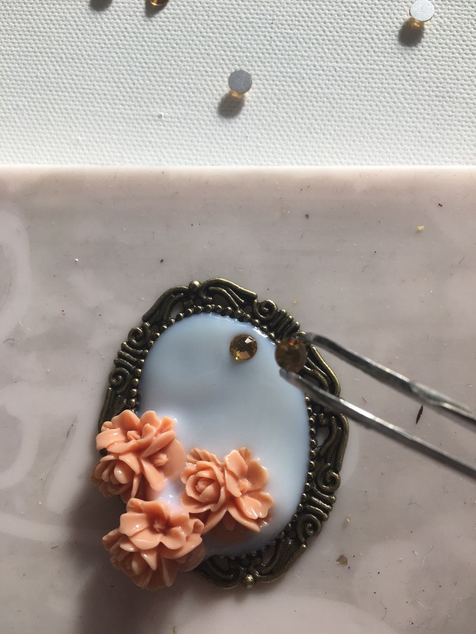 Using tweezers, I added my gems to one side make sure to LIGHTLY tap them down into the liquid glass.