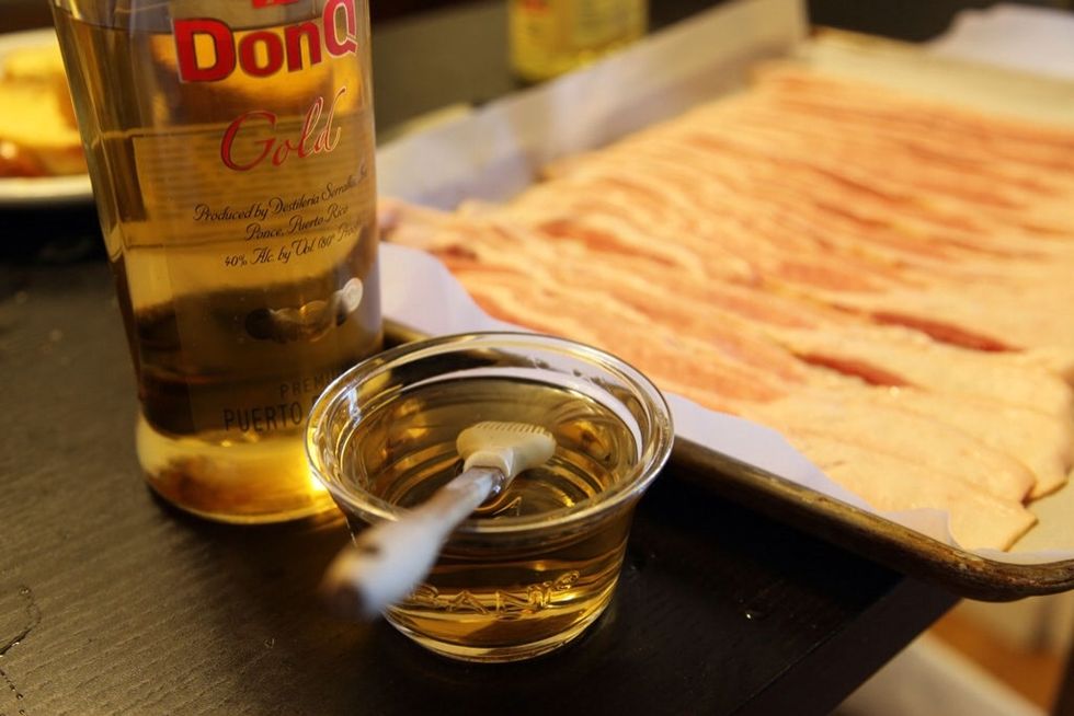 Using your basting brush, drizzle and distribute Don Q Gold over the bacon.