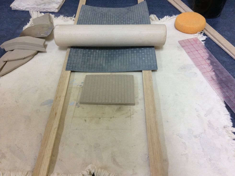 Using your desired texture mat, roll the clay again with the texture mat over the clay and wood slats. Keep your tile with an even thickness!
