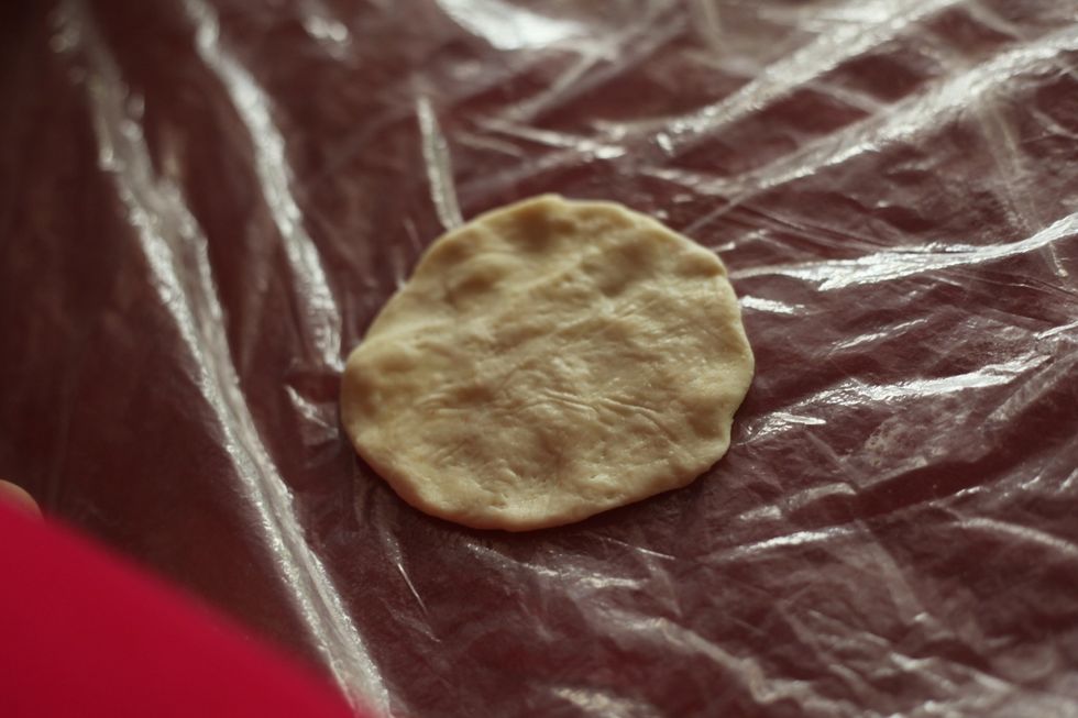 Using your fingers, flatten each dough out on your work bench. I've put down a plastic bag so I don't have to clean up oil residue from the kitchen bench. Genius I know, right! ;)