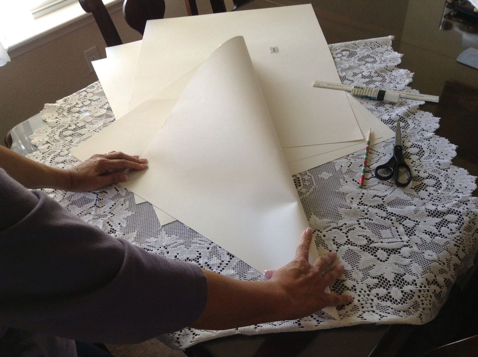 Using your first poster board, bring one of the corners down to align with the opposite edge of the poster board. Press along the folded edge to form a crease line.