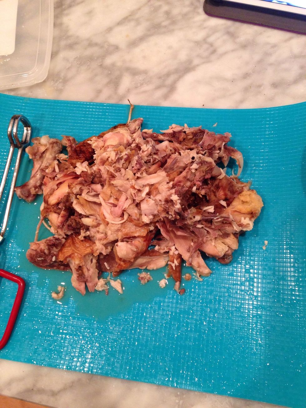 Using your hands, remove all the chicken meat from the bones.