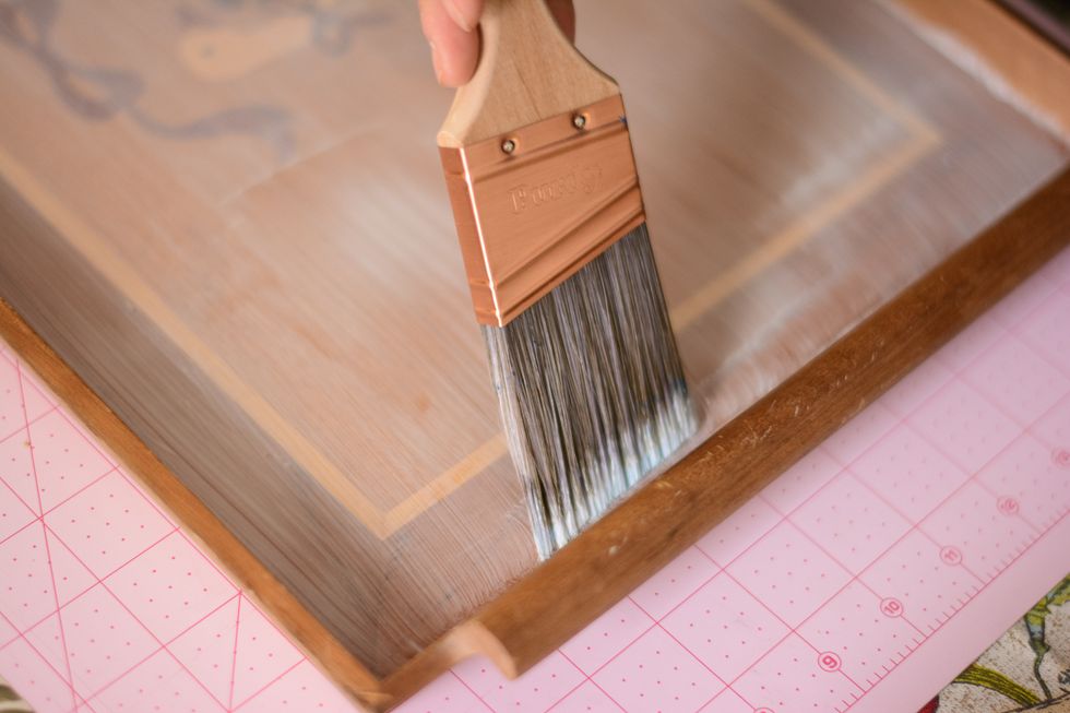 Using your paint brush, start applying the Mod Podge to your tray.  Layer it on fairly thin (we want to avoid bubbles!).  Try to keep your brush stokes going in one direction.