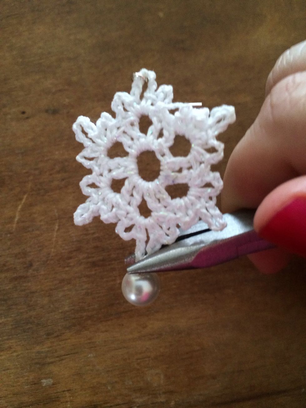 Using your pliers, wrap the excess wire around to form a loop. String the pearl through the bottom point if the snowflake. Using the pliers, close the loop around the base of the snowflake.