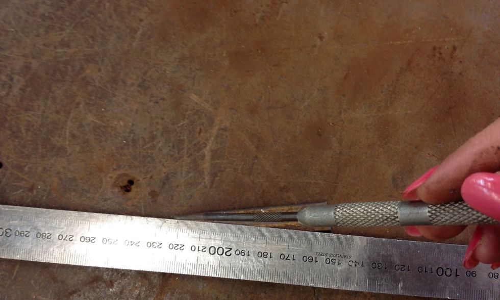 Using your ruler and scribe meausure a cross from the corner to corner and make an indent in the centre of the cross using your centre punch.