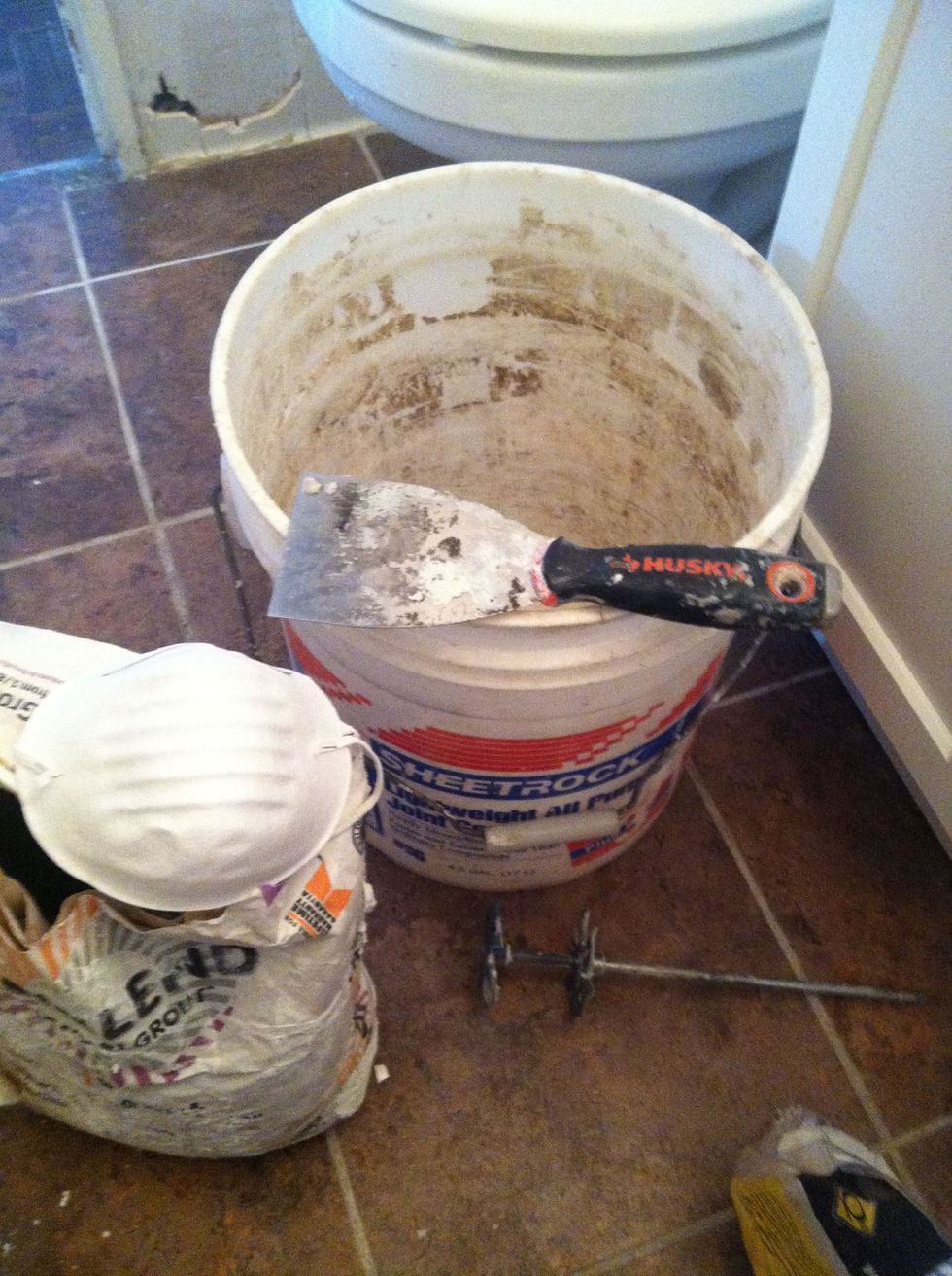 Utility bucket, sanded white grout, face mask , putty knife and mixer (not used)