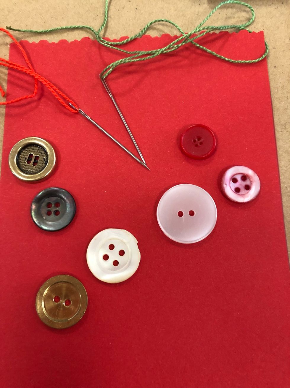 V\u00e4lj vilken tr\u00e5d du ska ha. Ta fram en spetsig broderin\u00e5l. Kolla s\u00e5 n\u00e5len f\u00e5r plats i h\u00e5len. Om du inte har tillg\u00e5ng till n\u00e5l och tr\u00e5d g\u00e5r det bra att s\u00e4tta fast knapparna med limpistol.