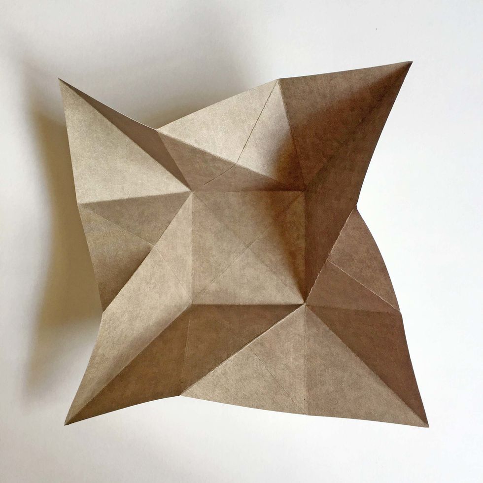 Valley fold the 4 corners of the the paper as shown...  As you do this, the 4 sides will raise up away from the central square...