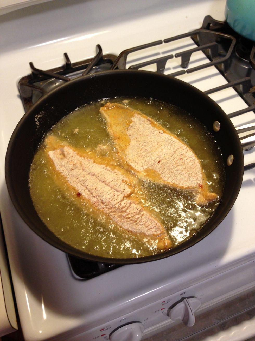 Very carefully, place the filets in the oil. It is going to splatter some, so be very careful. If it splatters way too much, you may have the heat set too high.