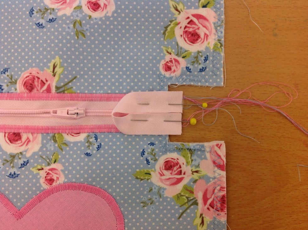 Vik bandet och n\u00e5la fast andra \u00e4nden p\u00e5 motsvarande sida av dragkedjan.