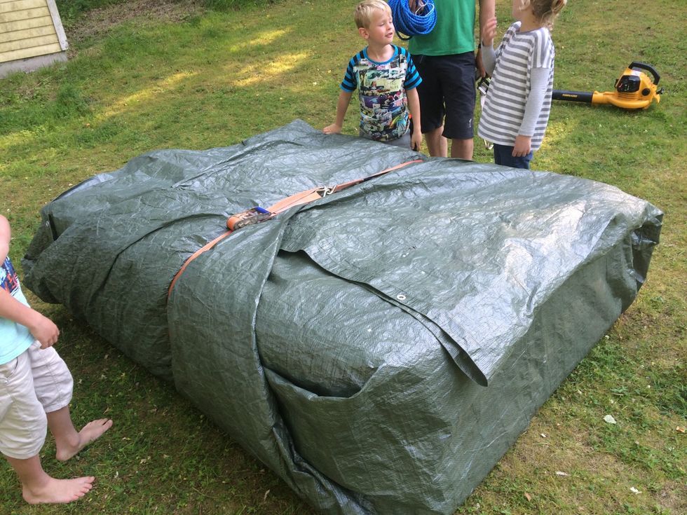 Vik ihop presenningen runt Restaformen och s\u00e4kra med ett sp\u00e4nnband.