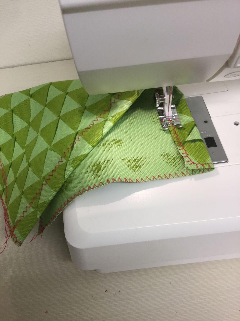 Vik in en bit av l\u00e5ngsidan. Sy fast den med zick-zack.