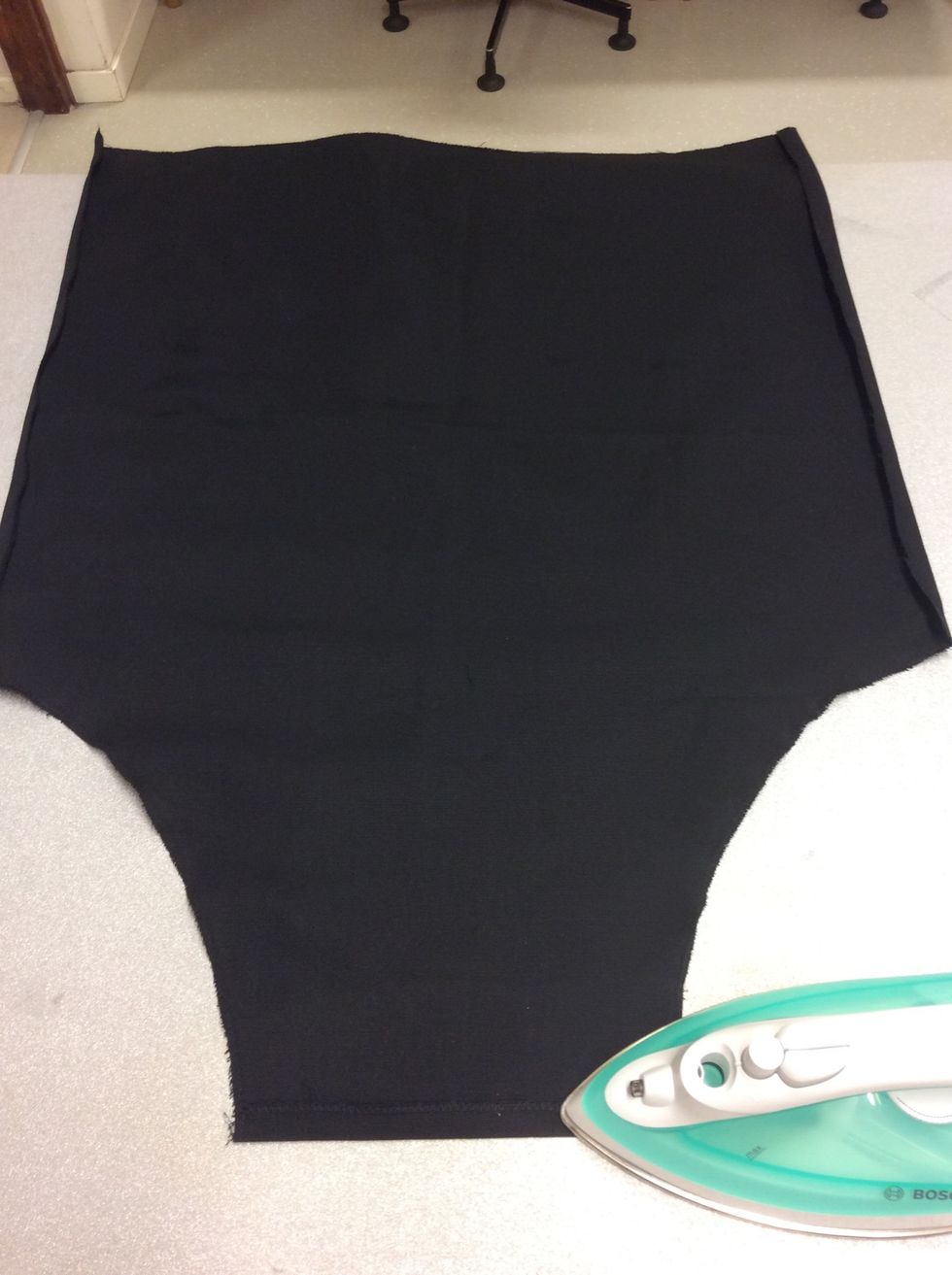 Vik in kanten upptill p\u00e5 f\u00f6rkl\u00e4det ca 1cm mot baksidan och pressa (stryk) den.