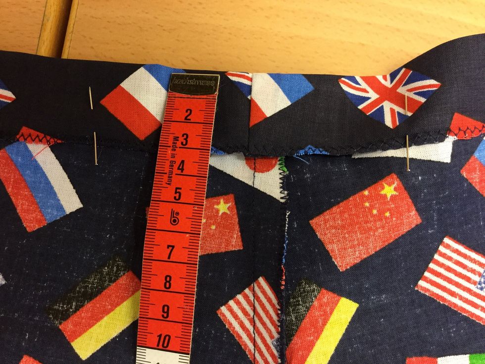 Vik, n\u00e5la och stryk fast en 3 cm f\u00e5ll i byxans \u00f6verkant.B\u00f6rja s\u00f6mmen baktill och l\u00e4mna en \u00f6ppning f\u00f6r res\u00e5rbandet.