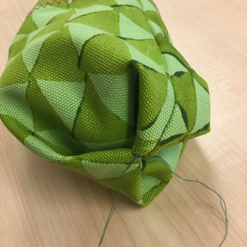 Vik ocks\u00e5 in andra h\u00f6rnet och sy n\u00e5gra stygn f\u00f6r att h\u00e5lla ihop det. Avsluta med ett g\u00e4ng knutar s\u00e5 att det s\u00e4kert sitter fast. Sen kan du klippa av tr\u00e5den n\u00e5gra millimeter ifr\u00e5n knuten.