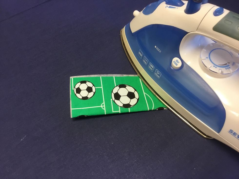 Vik tyget dubbelt och stryk. Vik noga p\u00e5 mitten.