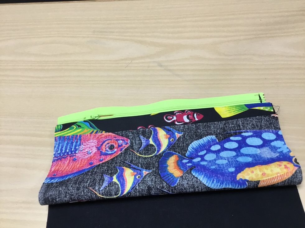 Vik upp nederkanten av fisktyget mot dragkedjan. Se n\u00e4sta bild.