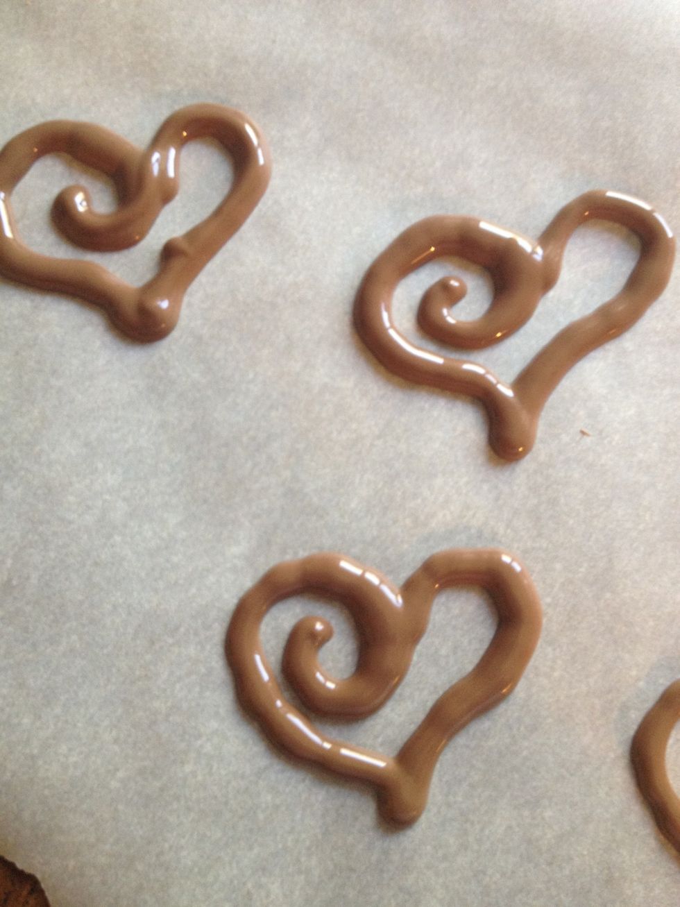 Wait a bit for the chocolate to cool, it makes piping much more manageable. Pipe whatever design you like onto parchment paper. Once your done, place in fridge and wait to harden