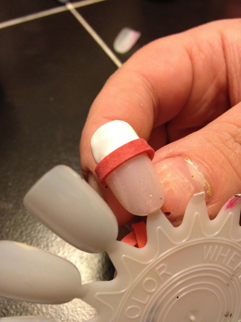 Wait for it to dry, you can loosen up the rubber band, then slide down, but there is going to be wet polish so don't let that touch the nail :)