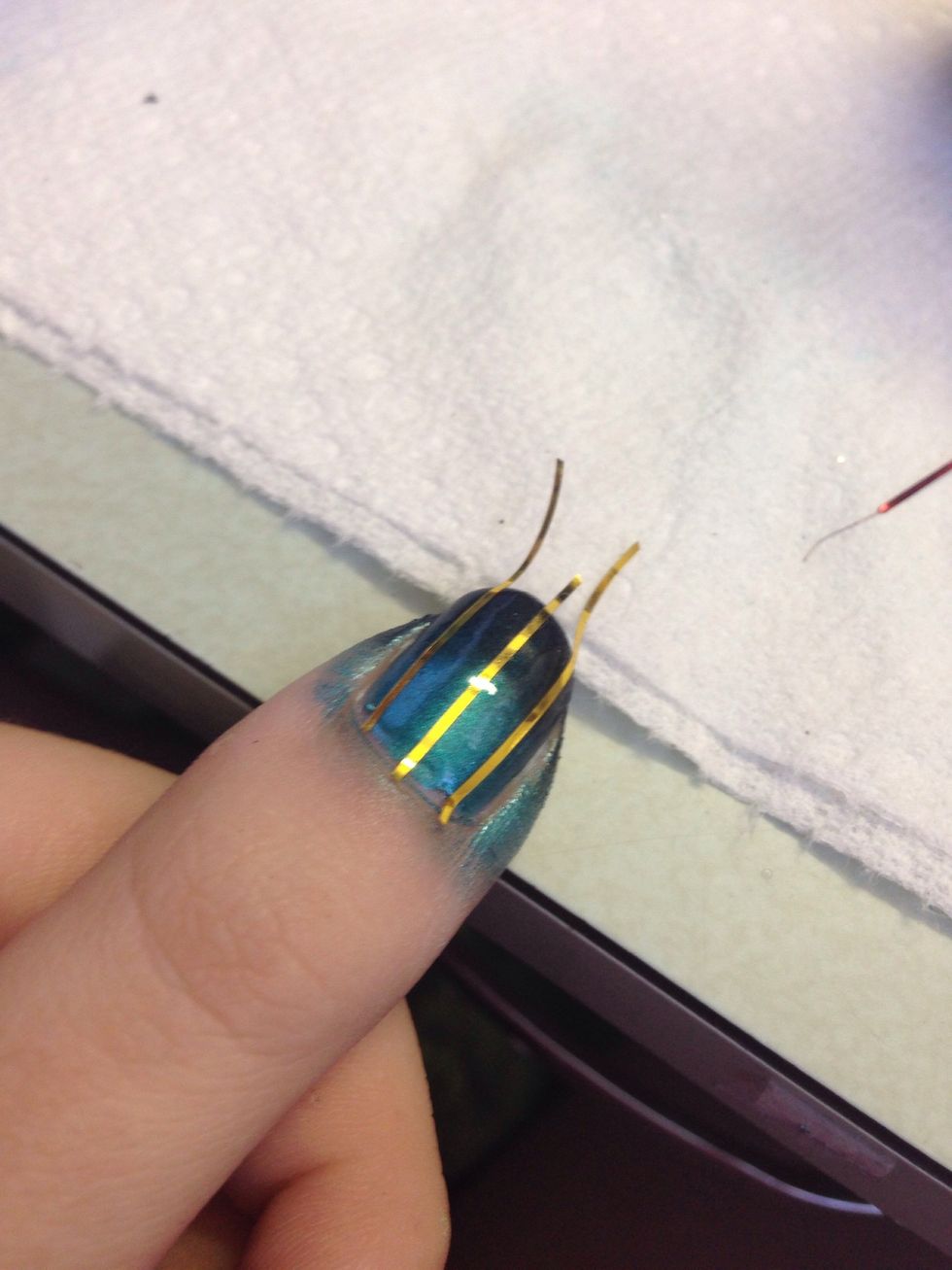 Wait for the first gradient to dry COMPLETELY! If you don't, the tape will peel up the polish. I put on a coat of seche vite topcoat to speed things along. Put 3 vertical pieces of striping tape on.