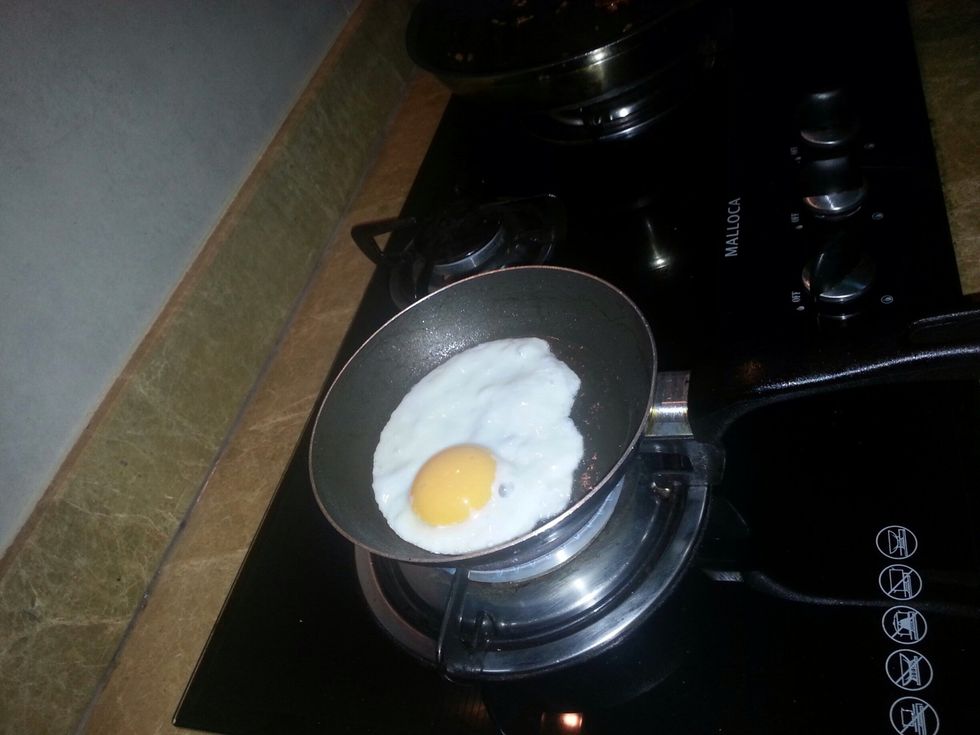Wait until the egg gets fried. If it's fried flip the egg over with the spatchula.