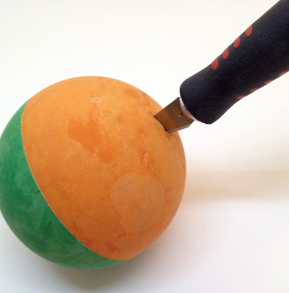 Warning: Kids should be supervised for the next few steps. Cut a small hole into the ball with the craft knife. Don't worry if the cut is too large as we will glue it shut later.