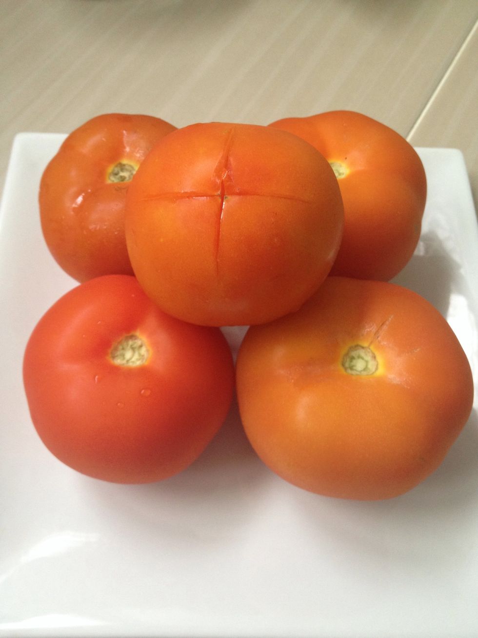 Wash and lightly cut the tomatoes to make an X
