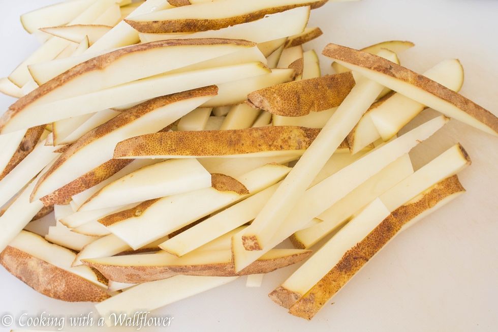 Wash and scrub the potatoes thoroughly and then dry them. Cut the potatoes into either 1 inch cubes or into \u00bd inch thick sticks.
