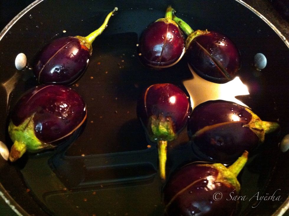 Wash the eggplants in salt water to get the bitterness out. Make slits in opposite directions on the bottom of the eggplant. Don't remove the crown it is needed.