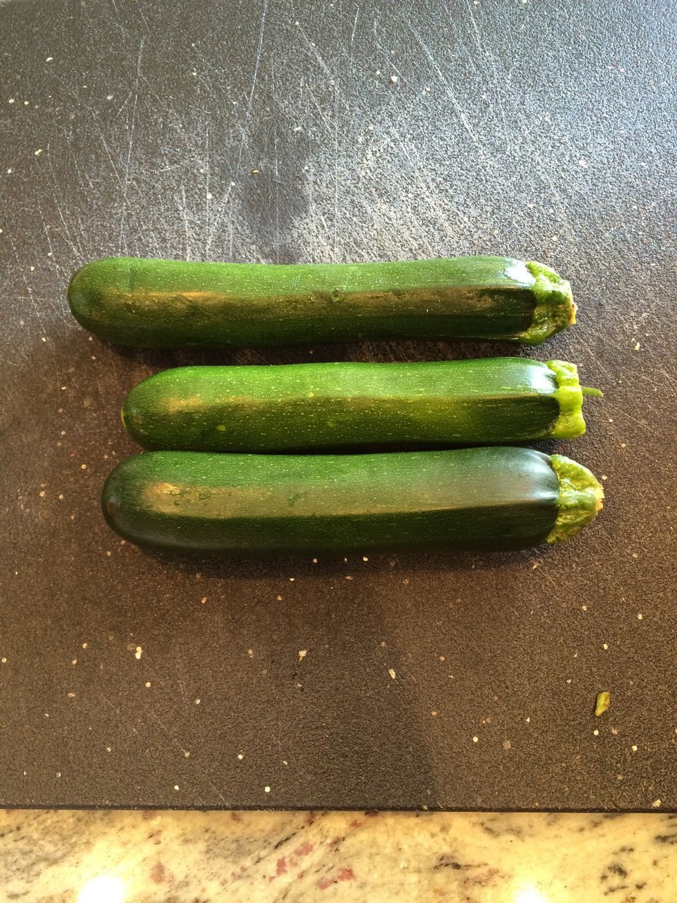 Wash the zucchini and line it up on the cutting board.