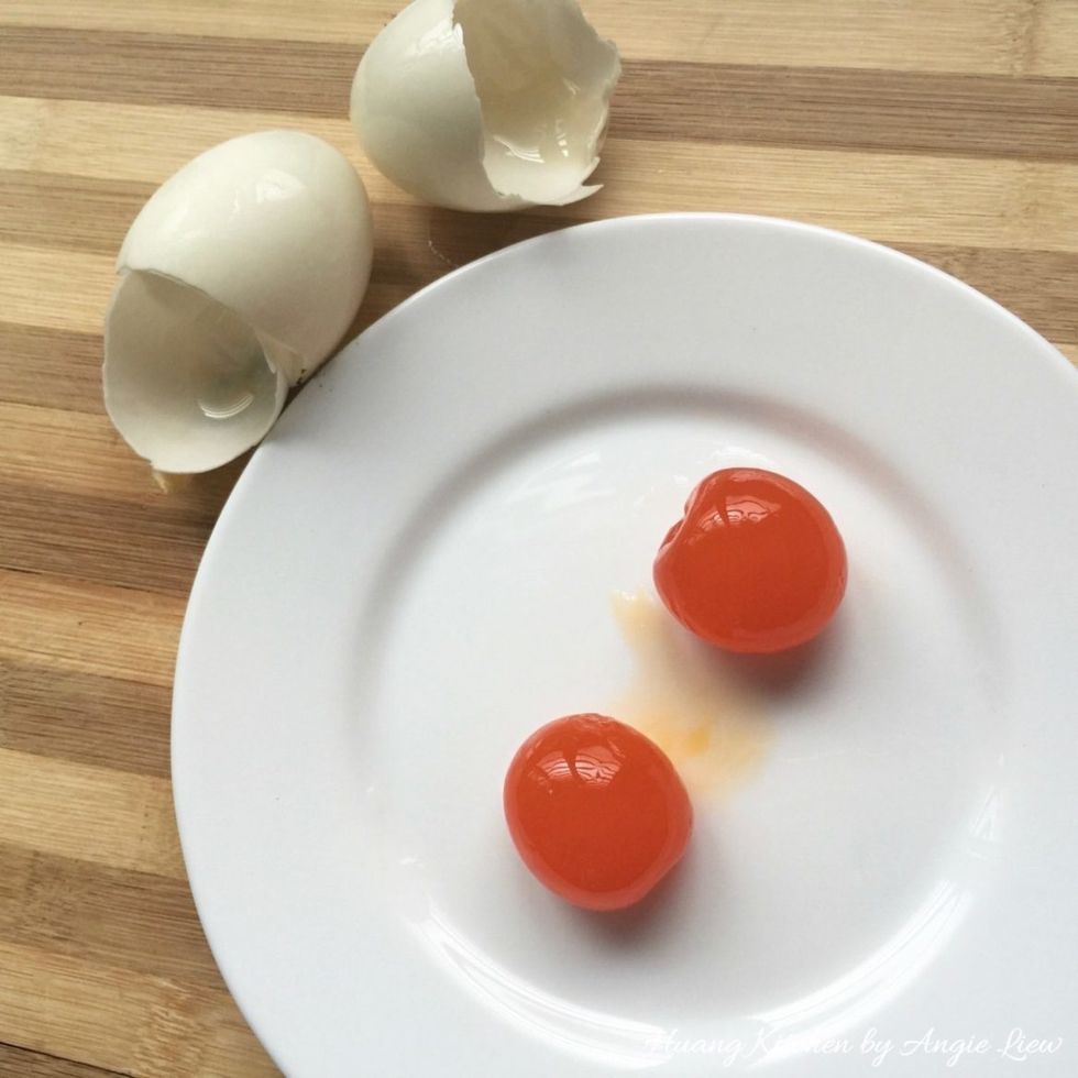 Wash to remove charcoal paste from salted eggs. Then break the shells and retain the egg yolks.