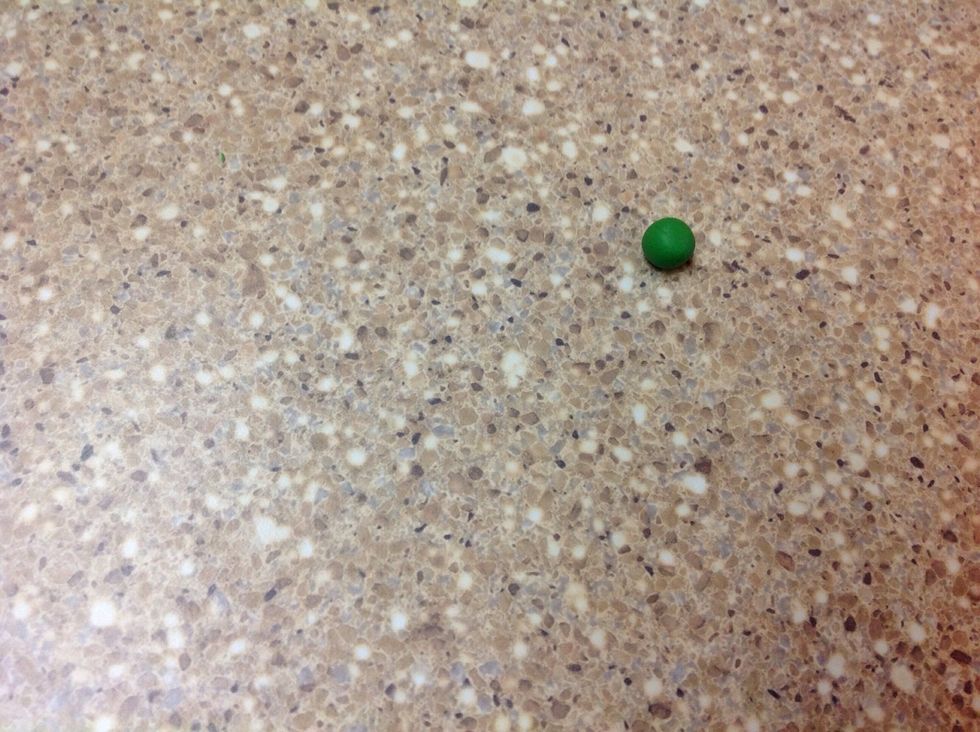 Wash your hands thoroughly before warming up the green clay. Pinch off a small piece of the clay, form a ball and place it on the hard surface.