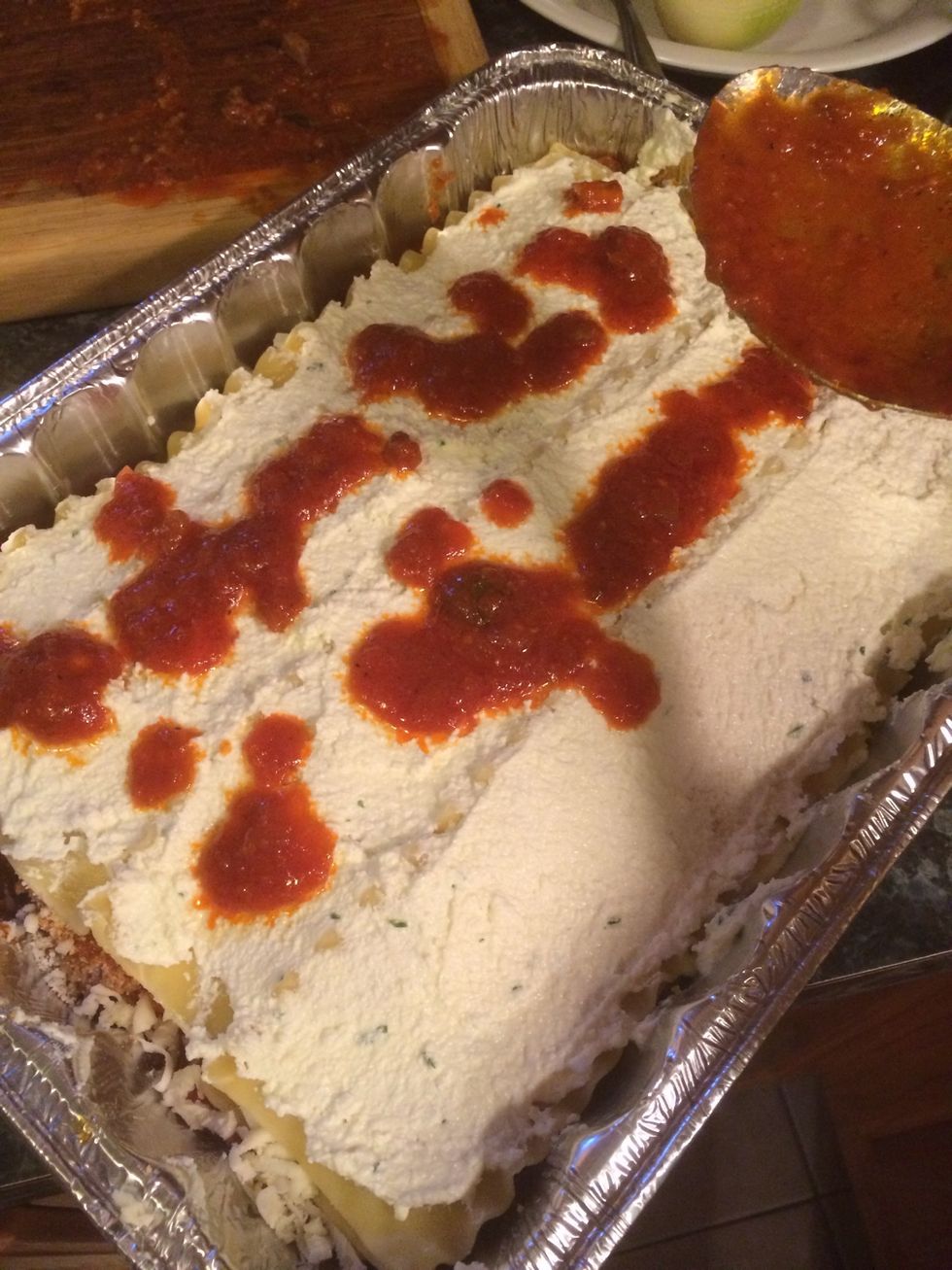 We have reached our final layer which is the top. We will spread some ricotta first, then pour some sauce over it.