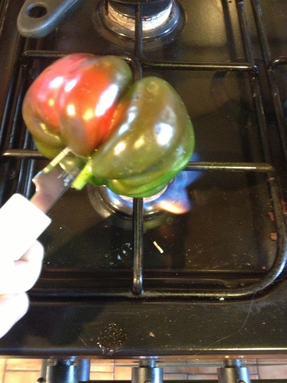 We're going to burn the skin off the pepper. Put it directly in the flame until it is black.
