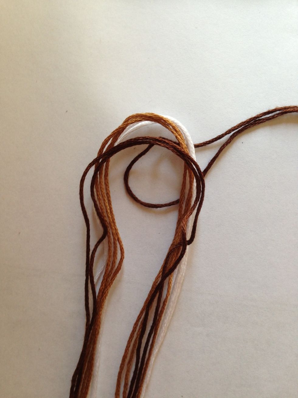 We're going to make a larks head knot at the center of the folds of the string. Place your loop under the fold...