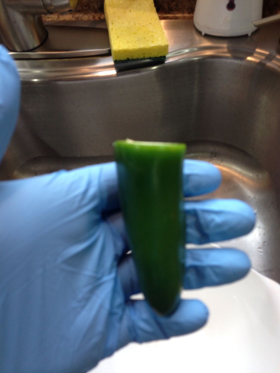 Wearing gloves take the top off the pepper