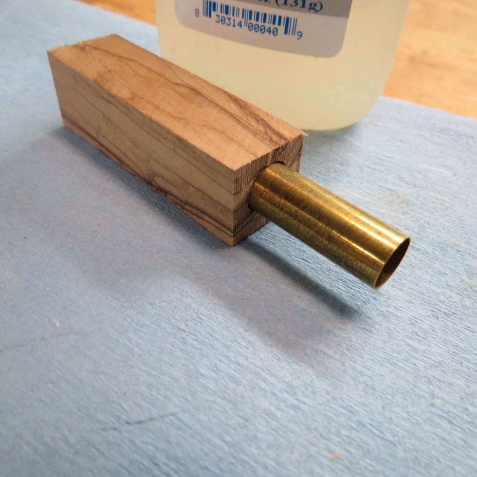 Wearing rubber gloves, grab the tube with one hand and hold the glue bottle over the tube. Apply the glue on the tube and with other hand twirl the tube into the drilled blank. CA glue dries fast!