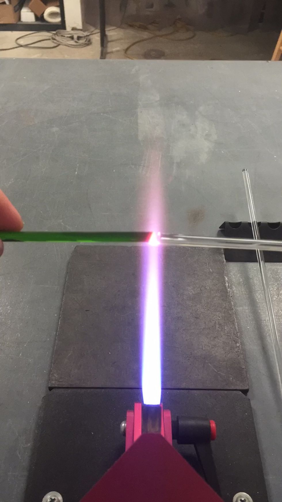Weld the Thallo to your punty by heating both ends and attaching them together. Direct the flame onto the Thallo and gather it into a ball. Avoid heating the punty so it doesn't mix with your color.