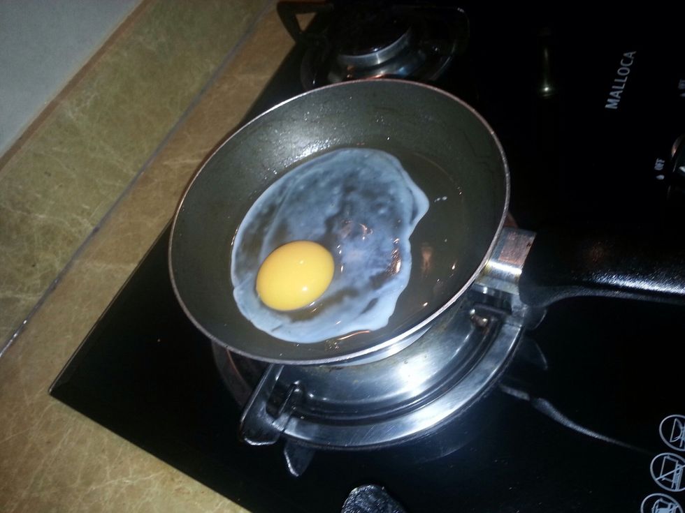Well, now it's a time to fry the egg. Get the small frying pan and do the same thing what you did for the big frying pan. Pour the cooking oil around the frying pan them crack the egg and out it in.