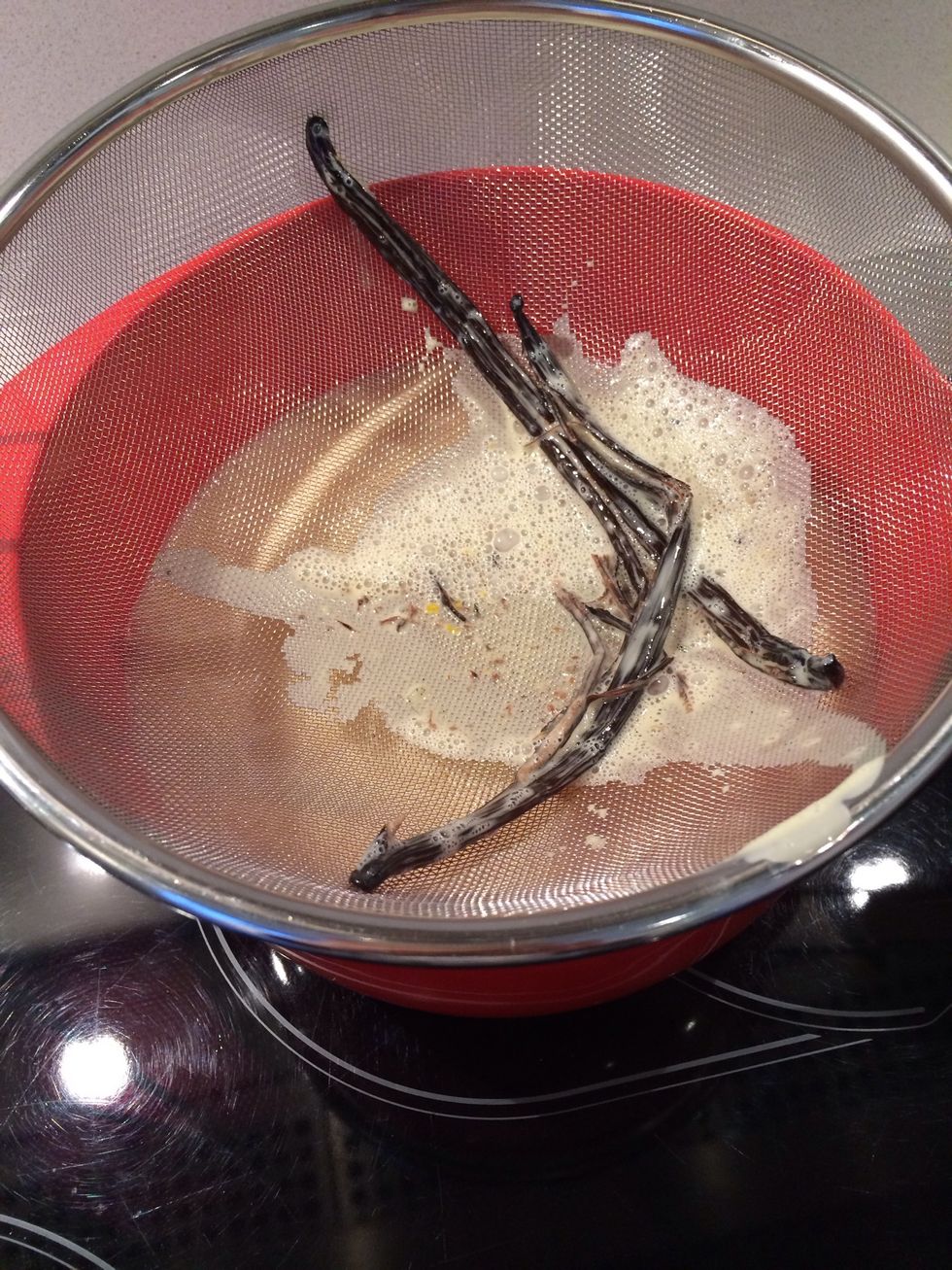 When all the cream is poured over the egg yolk strain them to remove any coagulated eggs and the vanilla bean