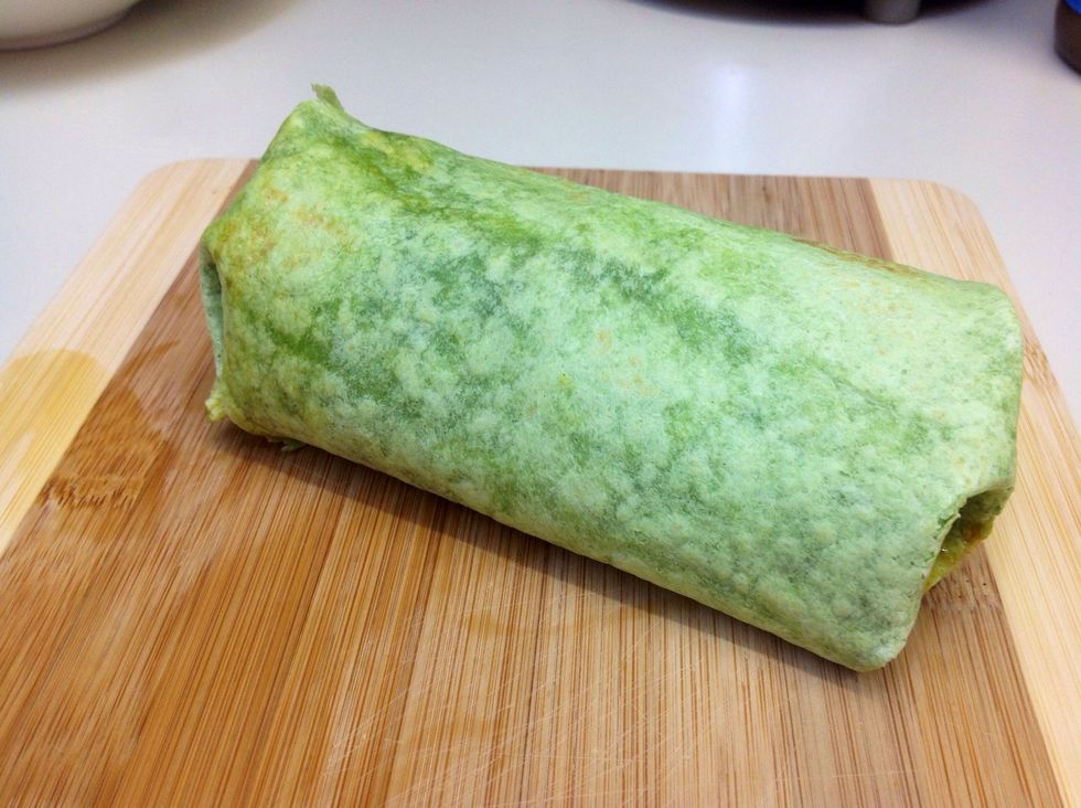 When all the ingredients have been added to the wrap securely tighten the spinach wrap using the surface to roll against and finish by tucking both ends in.