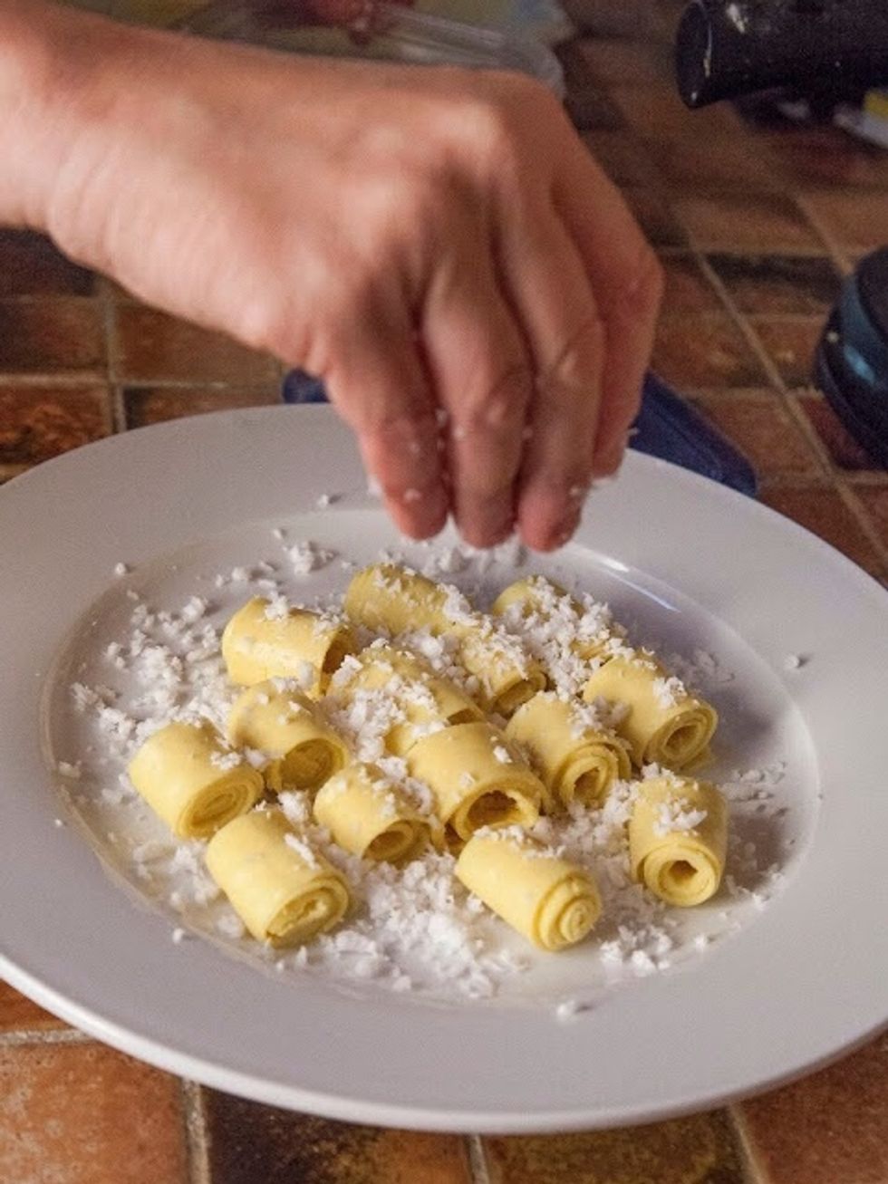 When all the khandvi have been rolled, arrange them nicely on a serving plate. Sprinkle them with the grated coconut.