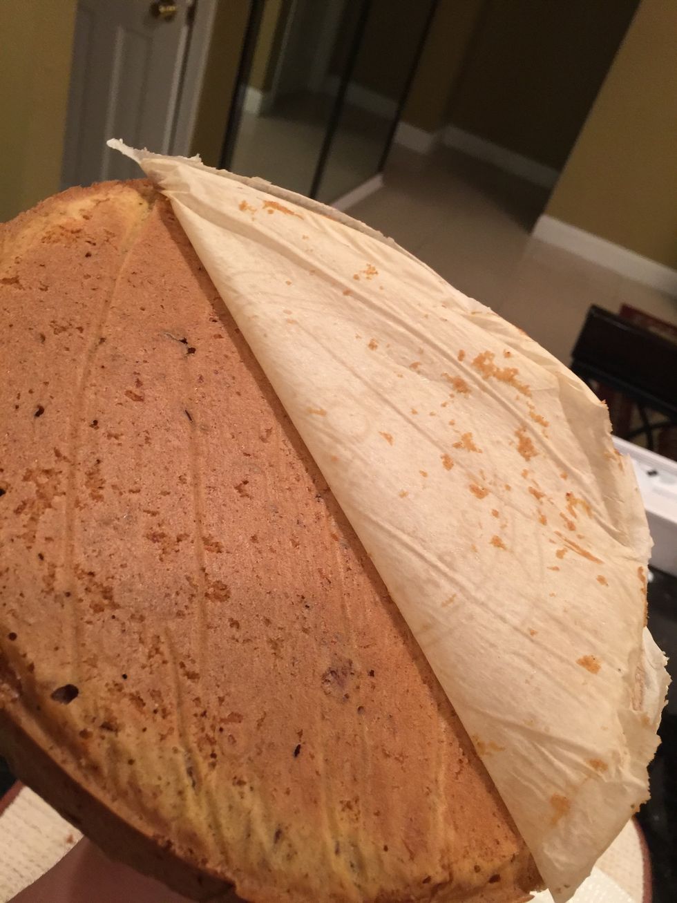 When cake is completely cool release it from springform pan by unlocking the latch. Then place one hand on top layer of cake and gently flip over and peel away parchment paper then place down on dish.