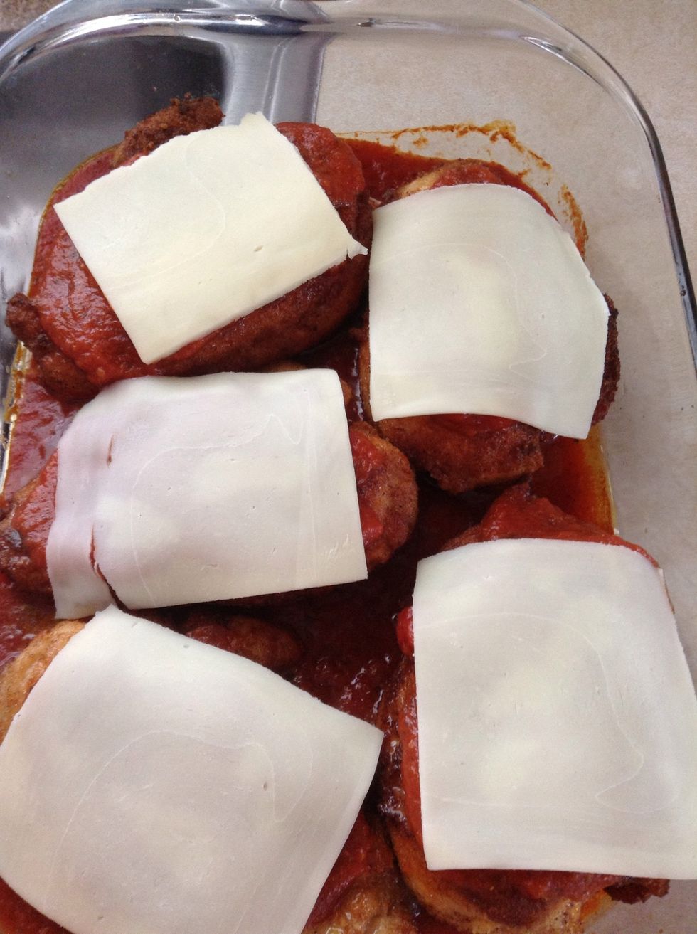 When chicken is fully cooked, add it to the pan, with a spoon add some more spaghetti sauce on top of the chicken breasts. Add a slice of mozzerella cheese to each,and put into oven.