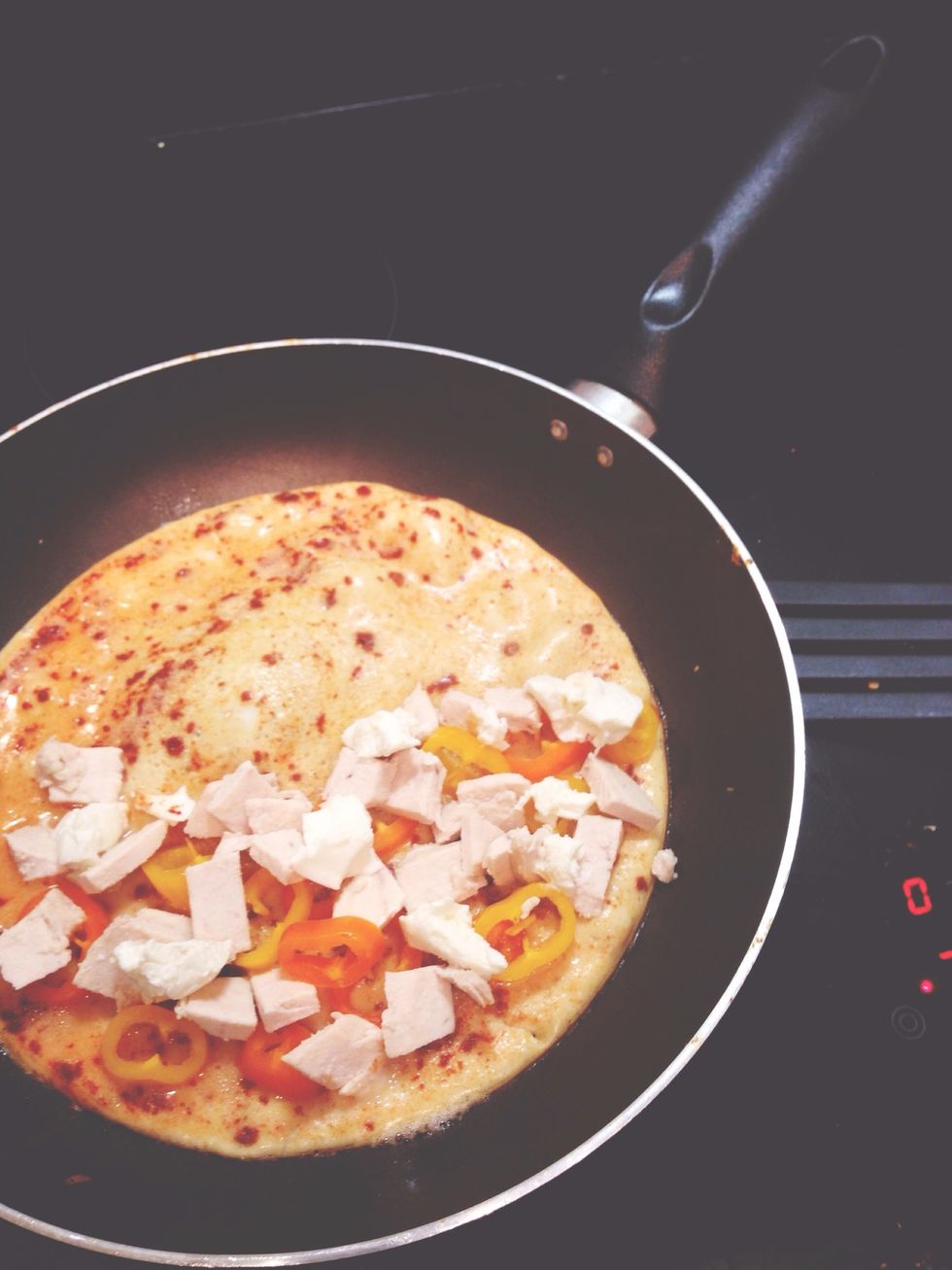When edge of omelette is golden add the sweet bell peppers,chicken and cream cheese. Cook for a couple of more mins until it starts to "boil".