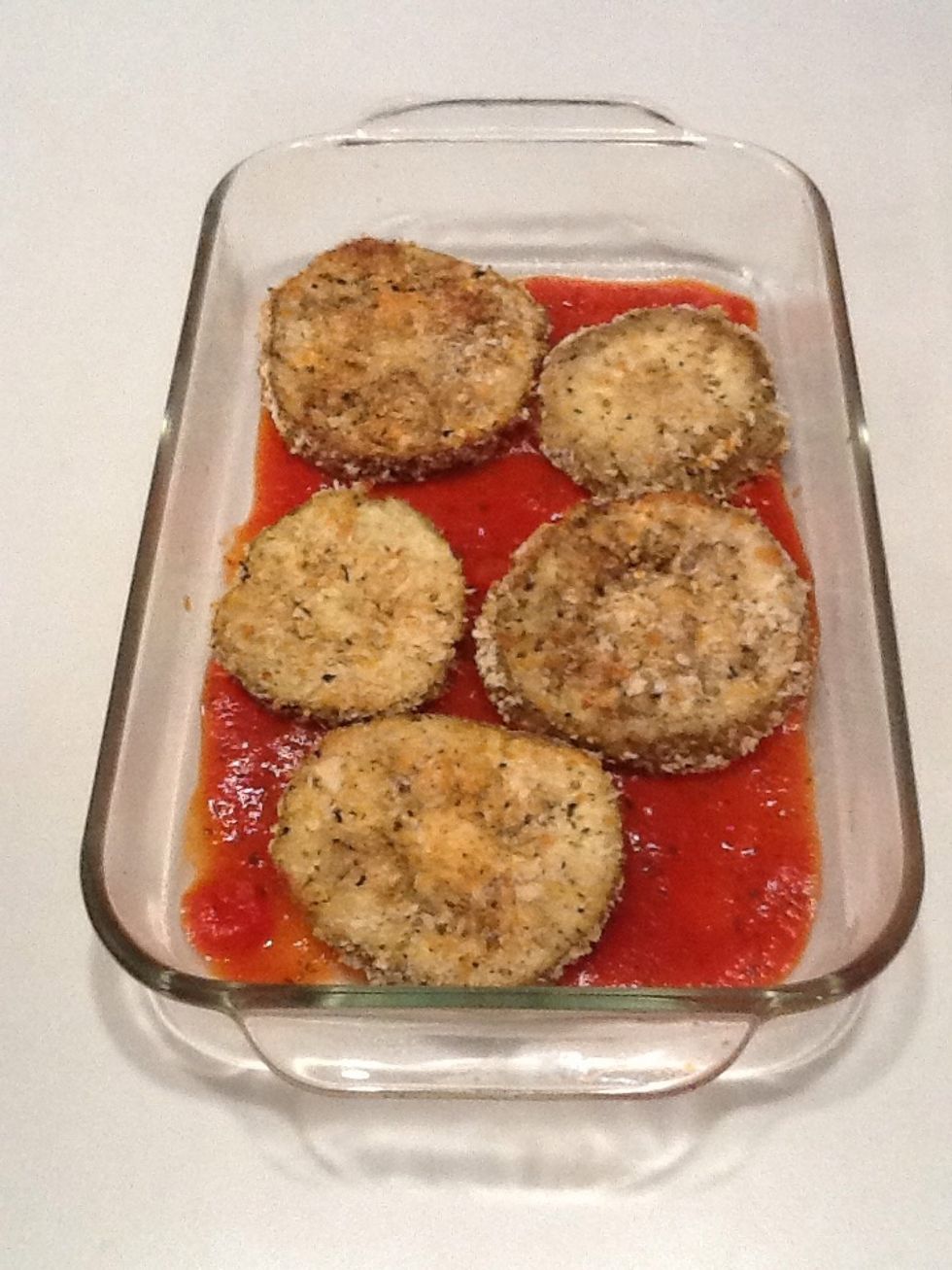 When eggplant is done, remove from oven and place half of the slices on the sauce.