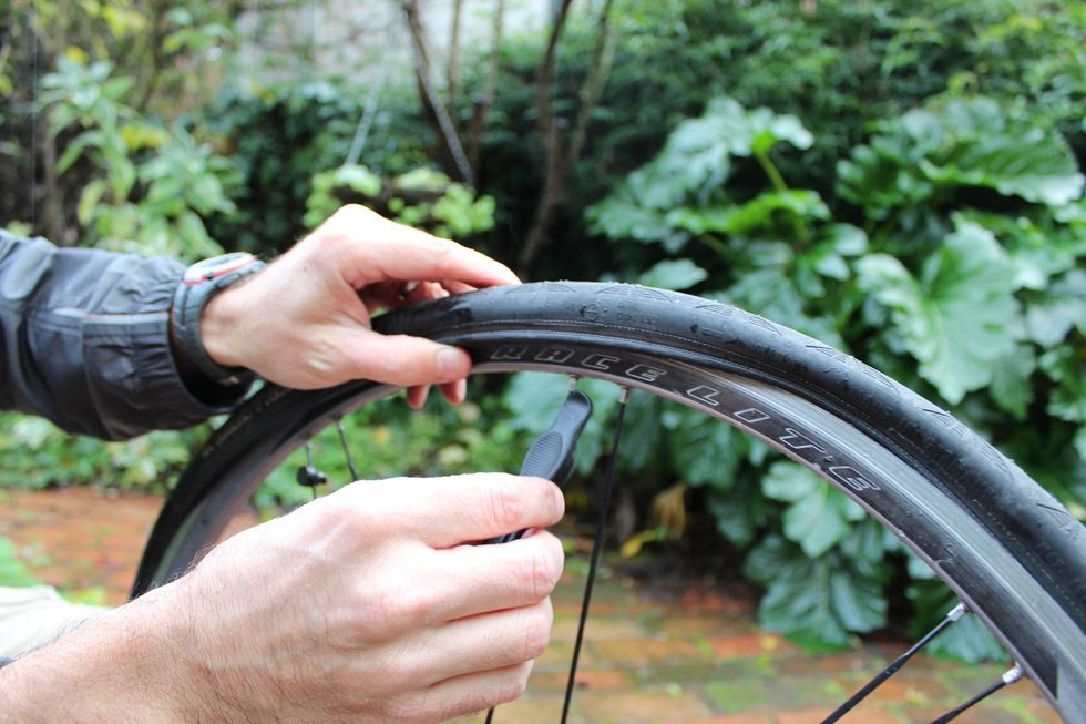 When it gets too hard to accomplish with just your hands, use your lever again until the entire tire is back under the rim - on both sides of the wheel.